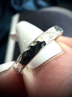 Silver ring with a textured band on a finger