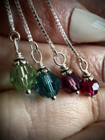 Four bead charm threaders being held in a hand.