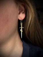 Earring with sword and moon design worn by a person