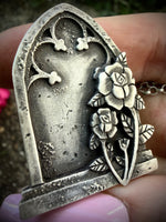 Closeup of a silver pendant with floral design held in hand