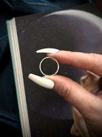 Hand holding a gold ring with a plain background