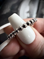 Silver beaded bracelet on a person's finger with a blurred background
