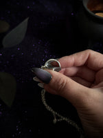 Hand holding silver pendant.
