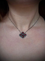 Necklace with a red gemstone pendant on a person's neck.