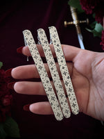 Three decorative celestial bookmarks held by a hand against a dark background with flowers and a sword.