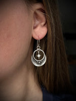 Close-up of a person wearing silver earrings with a star design.