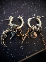 Pair of silver hoop earrings with intricate designs on a dark background