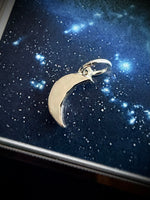 Silver moon-shaped pendant on a starry night sky background