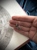 Hand holding a necklace with blue beads against an old map background